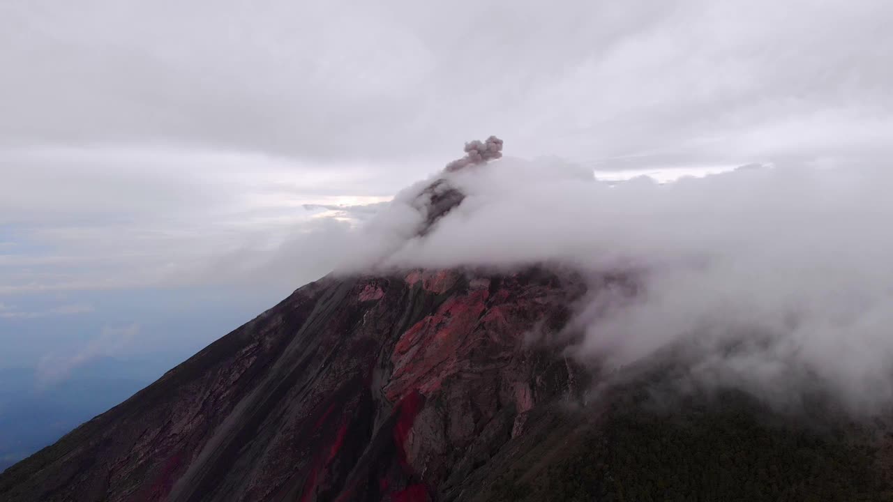 无人机捕捉到Volcán de Fuego火山的小喷发，笼罩在云层中，在危地马拉的安提瓜附近。视频素材