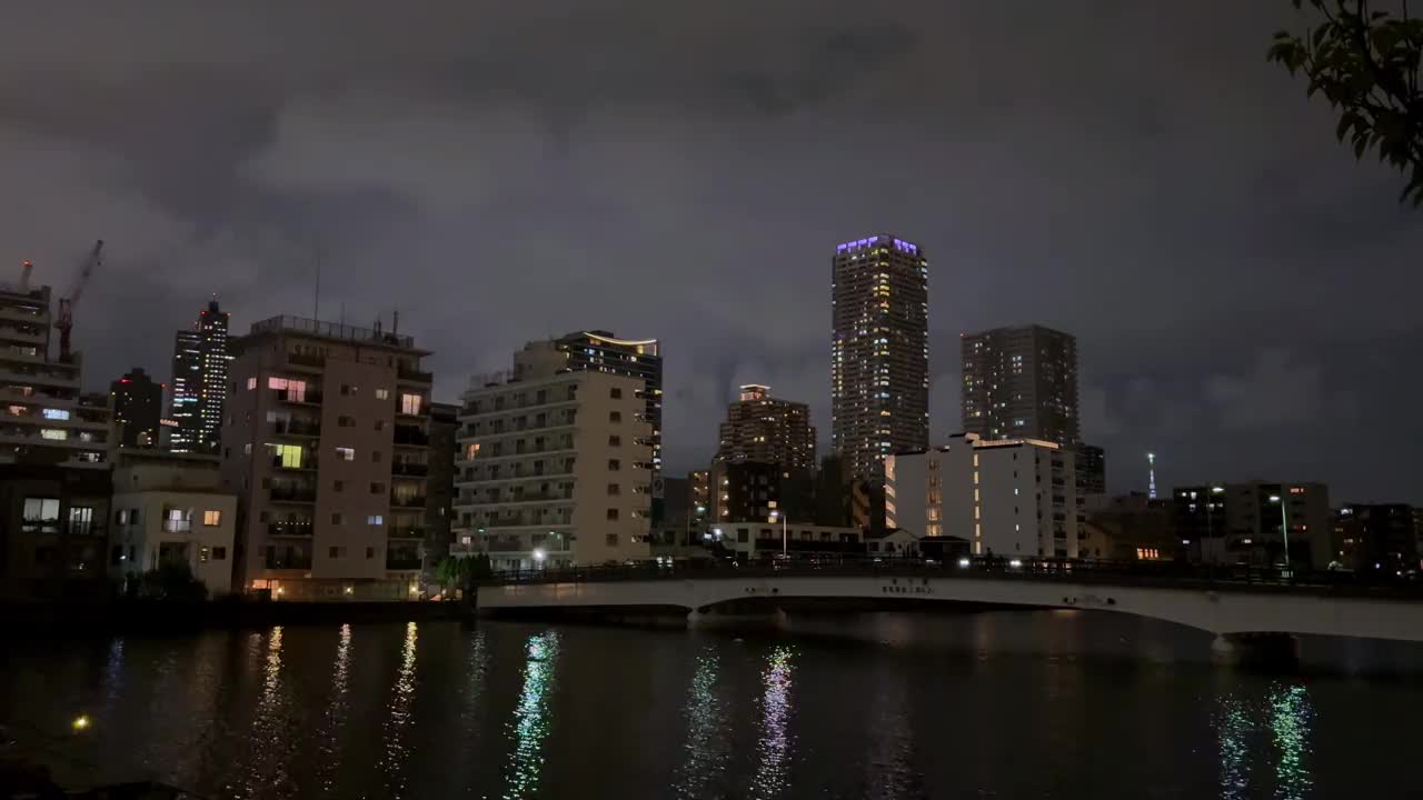 东京晴美区的摩天大楼照亮了夜空，头顶上酝酿着一场暴风雨视频下载