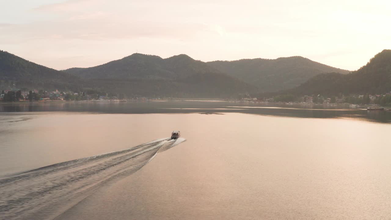 鸟瞰图，湖中有一艘船漂浮在水面上。峡谷里的湖，夕阳下漂浮的小船。视频下载