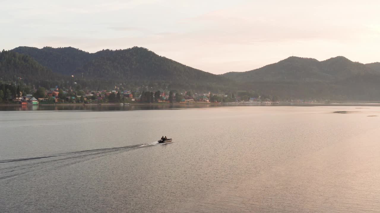 鸟瞰图，湖中有一艘船漂浮在水面上。峡谷里的湖，夕阳下漂浮的小船。视频素材