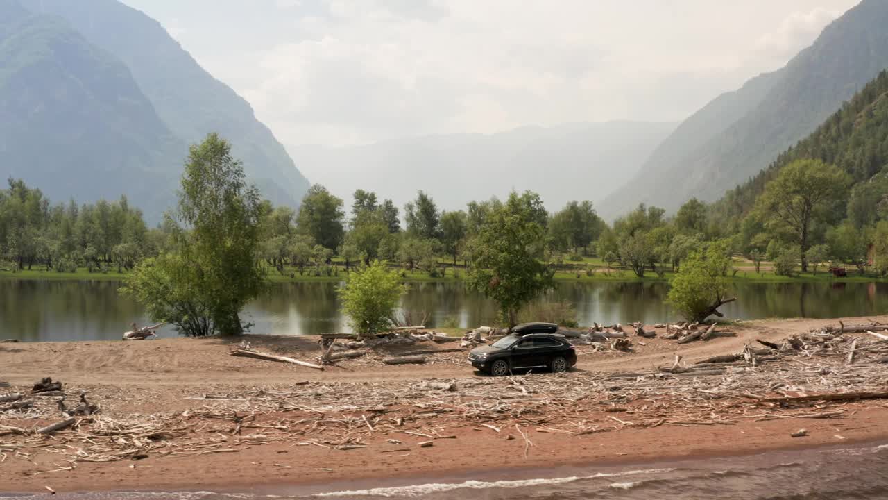 在美丽的山路上开车。自驾游概念。山林湖泊景观。在湖边岬角上行驶的汽车。汽车的鸟瞰图。视频下载