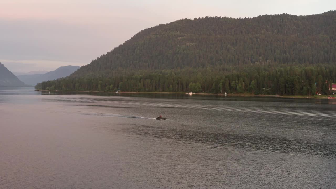 鸟瞰图，湖中有一艘船漂浮在水面上。峡谷里的湖，夕阳下漂浮的小船。视频下载