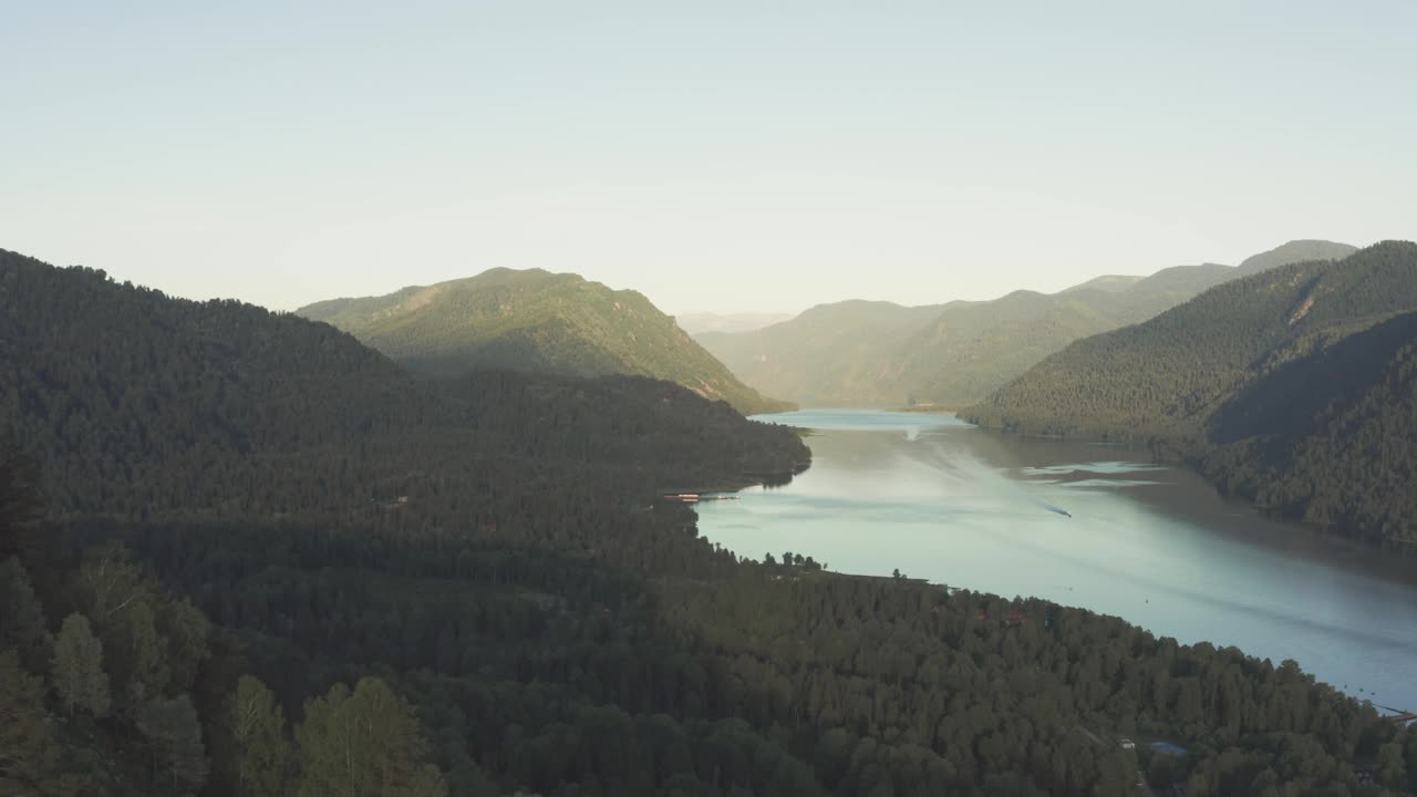 鸟瞰图，湖中有一艘船漂浮在水面上。峡谷里的湖，夕阳下漂浮的小船。视频素材