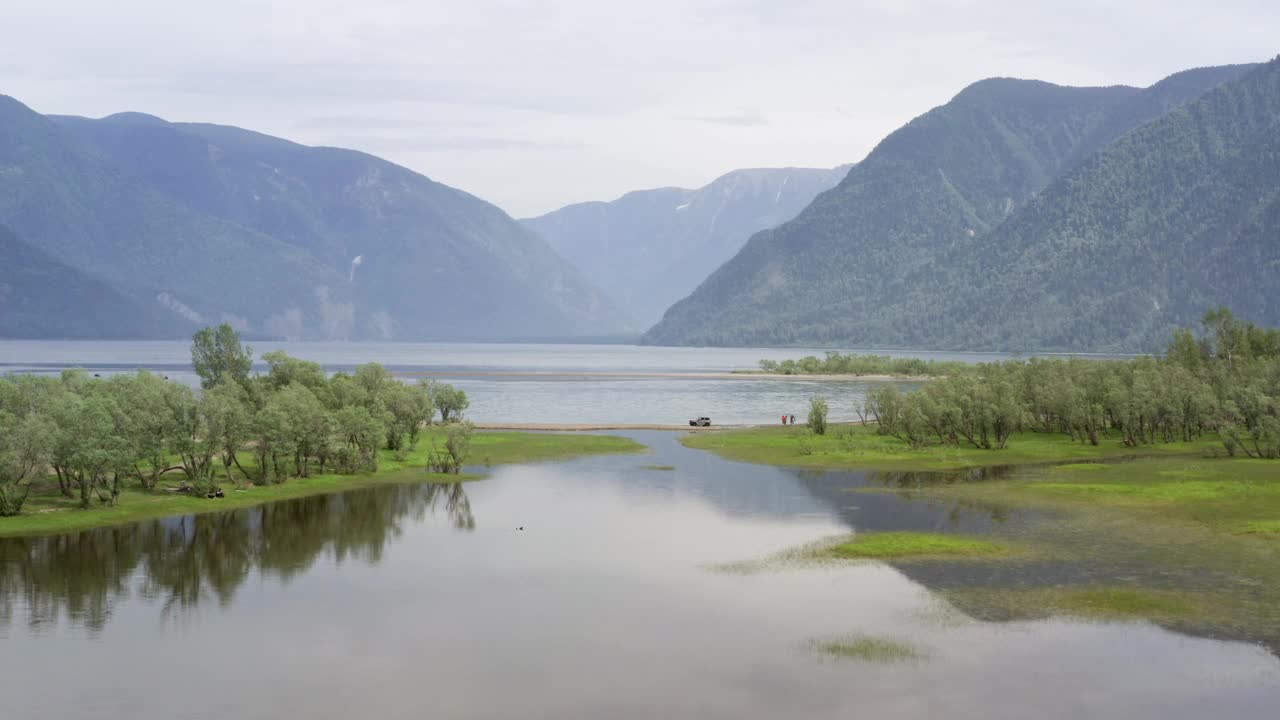 在美丽的山路上开车。自驾游概念。山林湖泊景观。在湖边岬角上行驶的汽车。汽车的鸟瞰图。视频素材