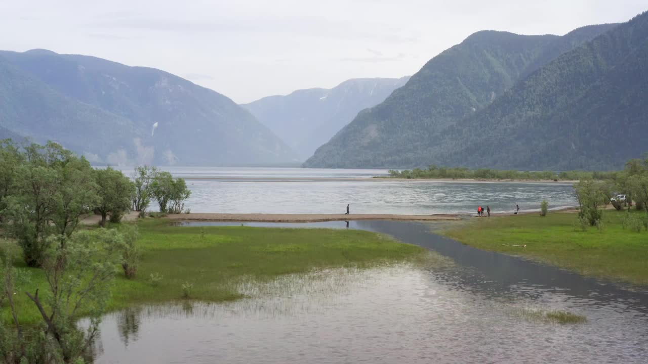 一个人走在美丽的山路上。自驾游概念。山林湖泊景观。一个人沿着湖边的岬角开车。鸟瞰图。视频素材