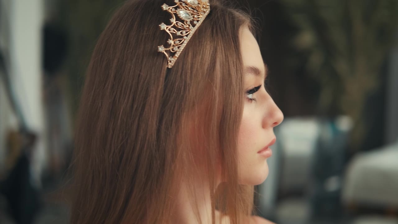 肖像近距离幻想美丽的女孩公主在金色的皇冠上。中世纪复古连衣裙。可爱年轻的脸。历史女性迷人的女王。时装模特看窗口工作室背景。视频素材画面1