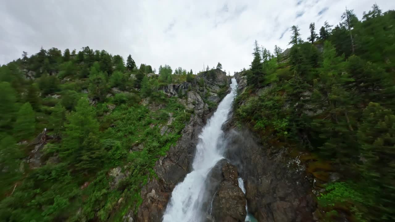 在宁静的自然环境中，一个令人惊叹的瀑布从郁郁葱葱的绿色山坡上倾泻而下视频素材