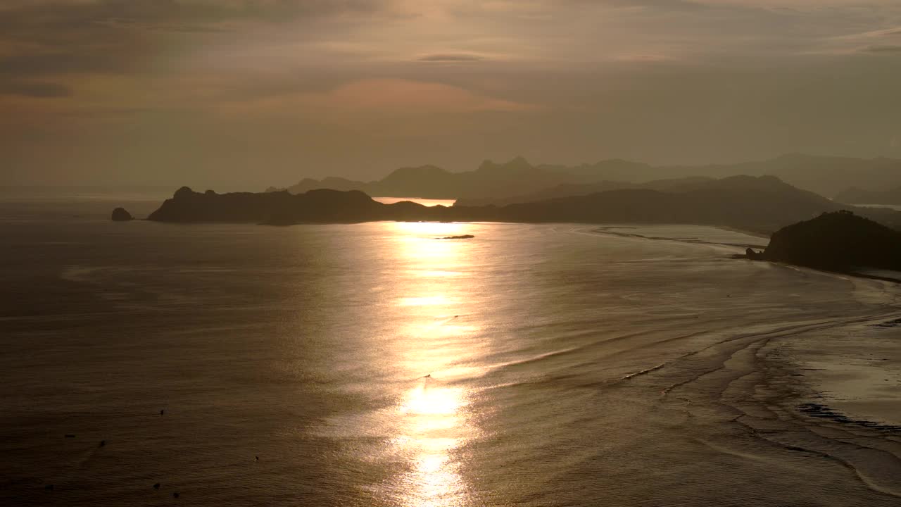 金色的日落反射在平静的海岸水域，远处的山脉在背景中视频素材