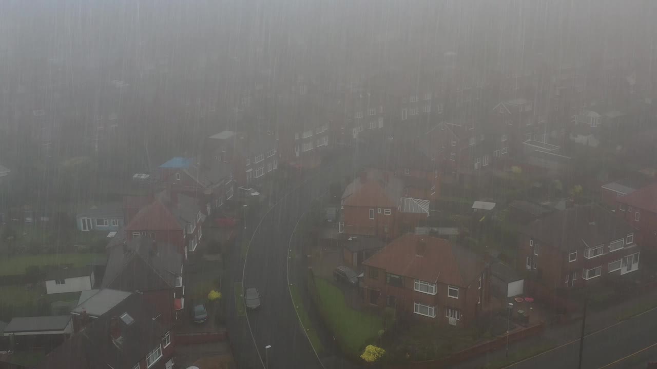 在大雾天的大雨中，航拍镜头飞过英国西约克郡利兹市中心的一个住宅区，展示了英国城市和城镇在一场严重的风暴中视频素材