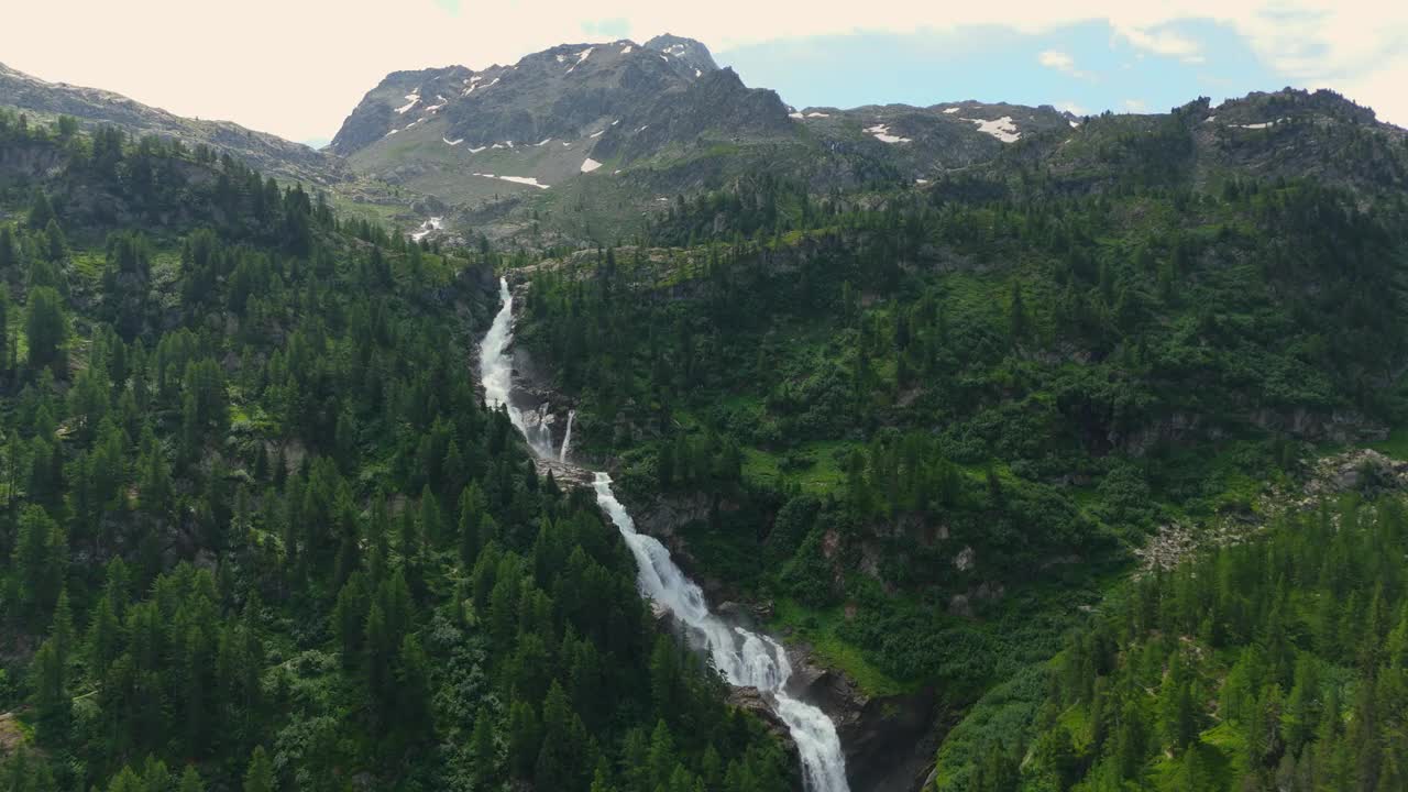 雄伟的瀑布穿过郁郁葱葱的意大利阿尔卑斯山，背景是山峰视频素材