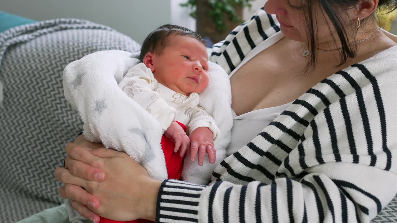 母亲抱着襁褓中的新生婴儿，在一个平静而有教养的家庭环境中享受着亲密的安静时刻视频素材