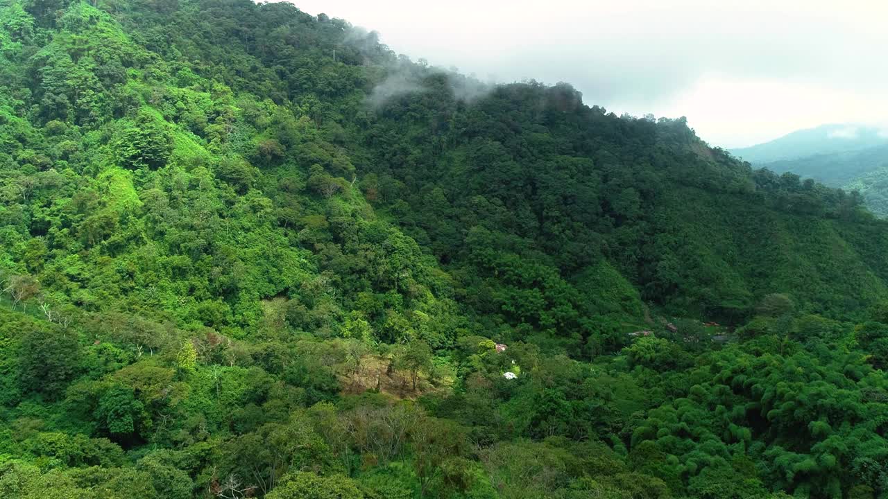 在多云的春日里，高高的青山环绕着山谷中的小村庄。视频素材