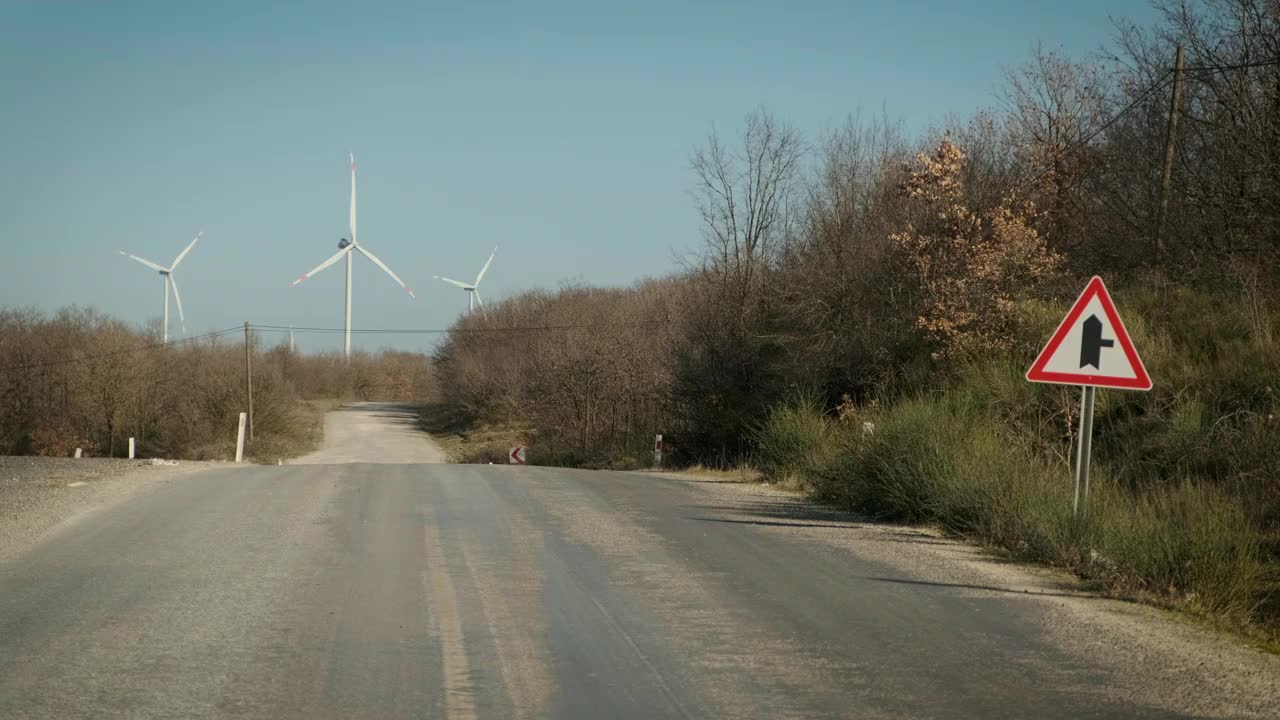 远处有风力涡轮机的乡村公路视频素材