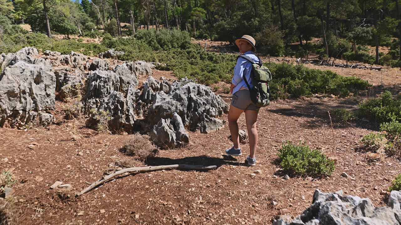 在郁郁葱葱的森林小径上徒步旅行的女人，享受大自然和户外冒险，在阳光明媚的日子里背着背包探索荒野，非常适合旅行和冒险者视频素材