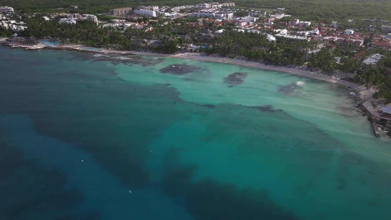 拍摄Bayahibe海岸，航拍清澈的海洋，美丽的沙滩和背景树木和度假村。多米尼加共和国。视频素材