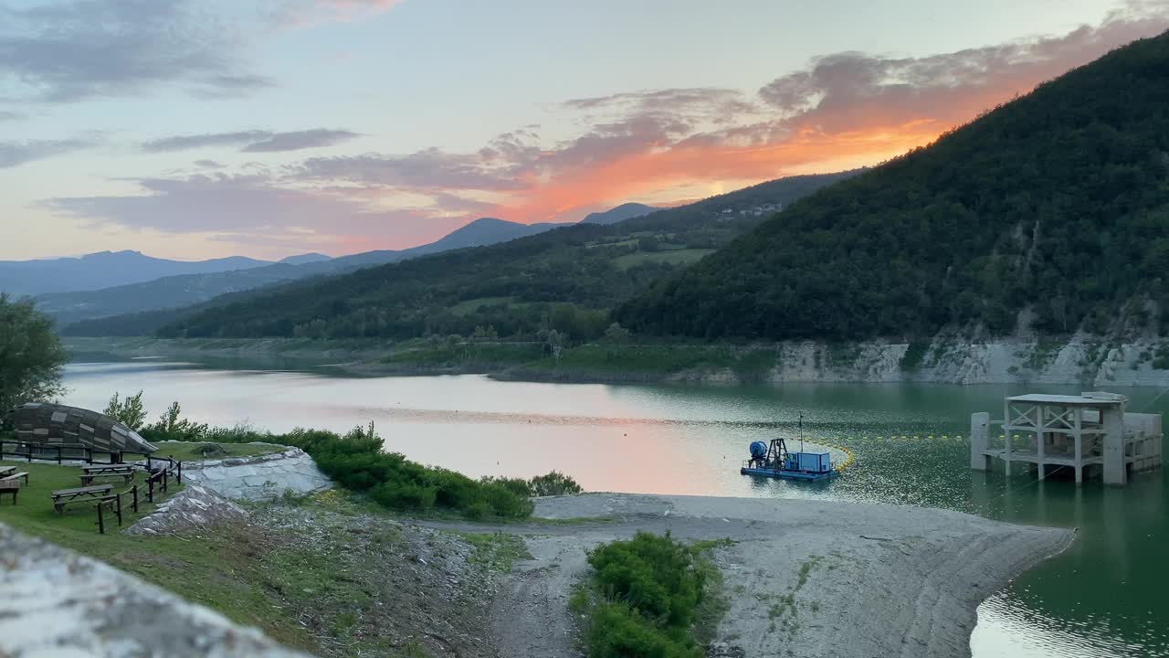 在意大利皮亚琴察的米尼亚诺大坝上，有船和风景优美的山湖上宁静的日落视频下载