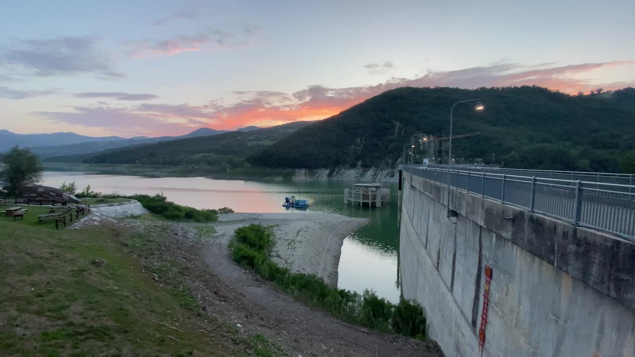 在意大利皮亚琴察的米尼亚诺大坝上，宁静的日落与船和风景优美的山间湖视频素材