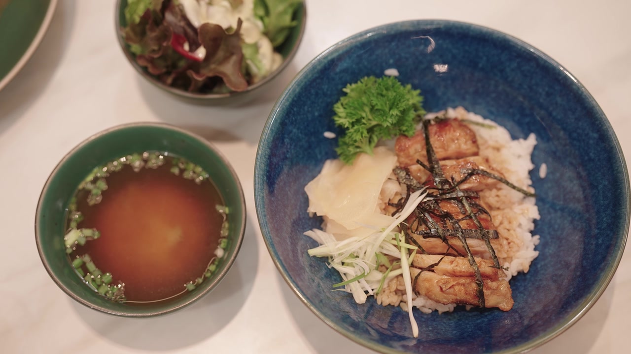 日式照烧鸡配米饭、味噌汤和沙拉摆放在餐桌上。视频素材画面2