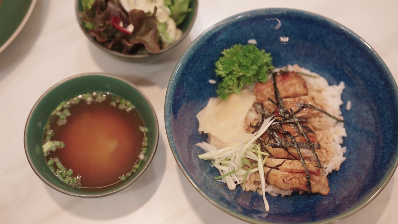 日式照烧鸡配米饭、味噌汤和沙拉摆放在餐桌上。视频素材画面3