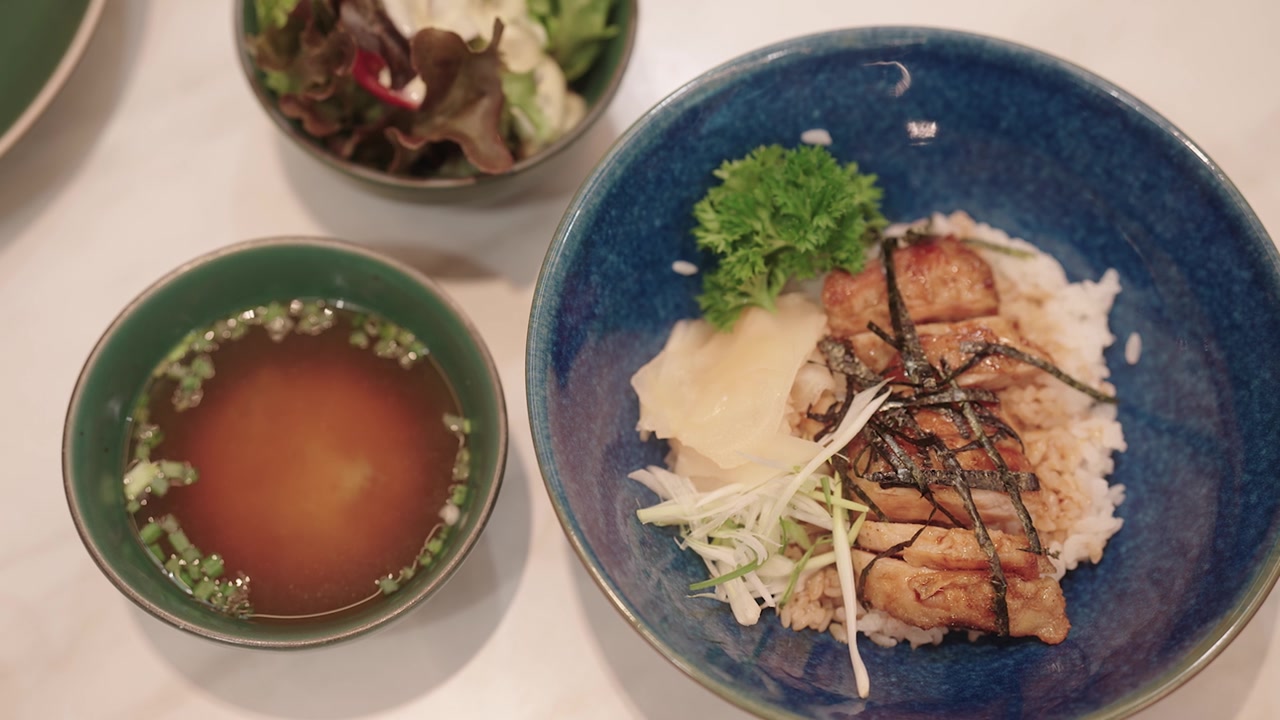 日式照烧鸡配米饭、味噌汤和沙拉摆放在餐桌上。视频素材画面4