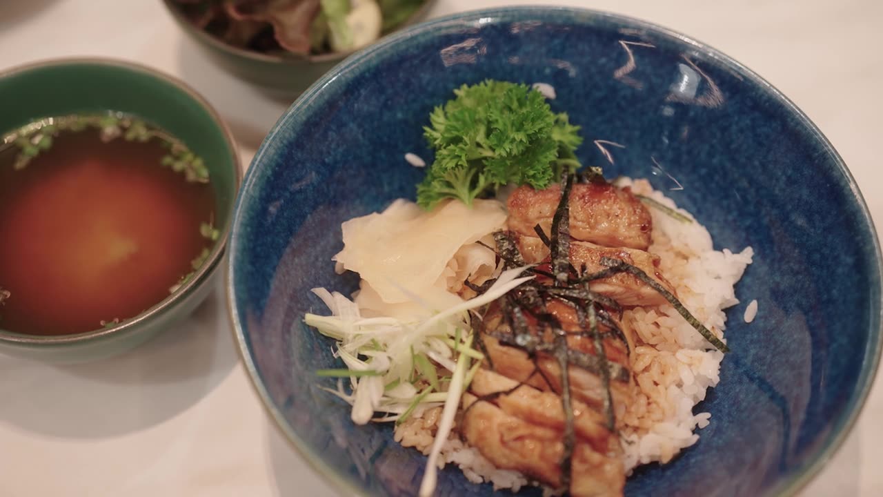 日式照烧鸡配米饭、味噌汤和沙拉摆放在餐桌上。视频素材画面1