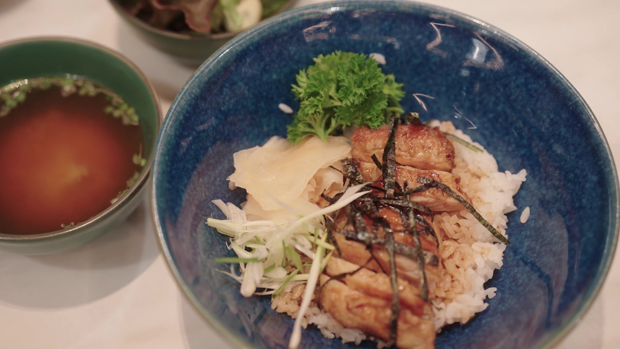 日式照烧鸡配米饭、味噌汤和沙拉摆放在餐桌上。视频素材画面2