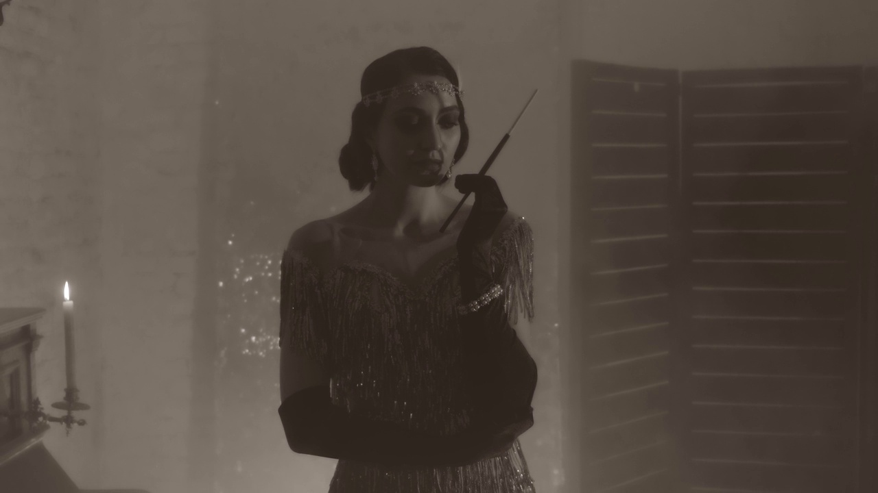黑白噪音风格的视频。年轻美丽性感的复古女性手持长烟嘴和香烟，吸烟者。复古女孩模特。40年代时尚裙装。背景是经典房间。视频素材画面4