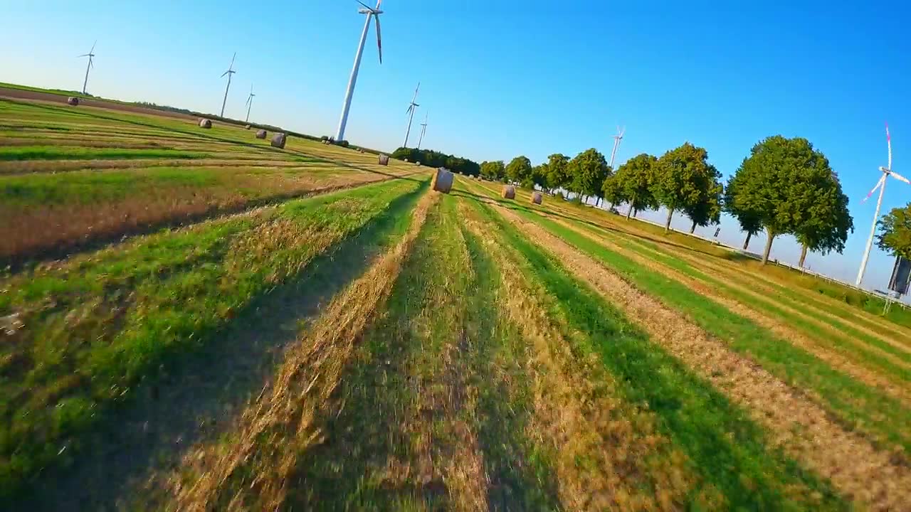 电影感FPV无人机飞行，穿越德国乡村的草垛和风力涡轮机视频素材画面1