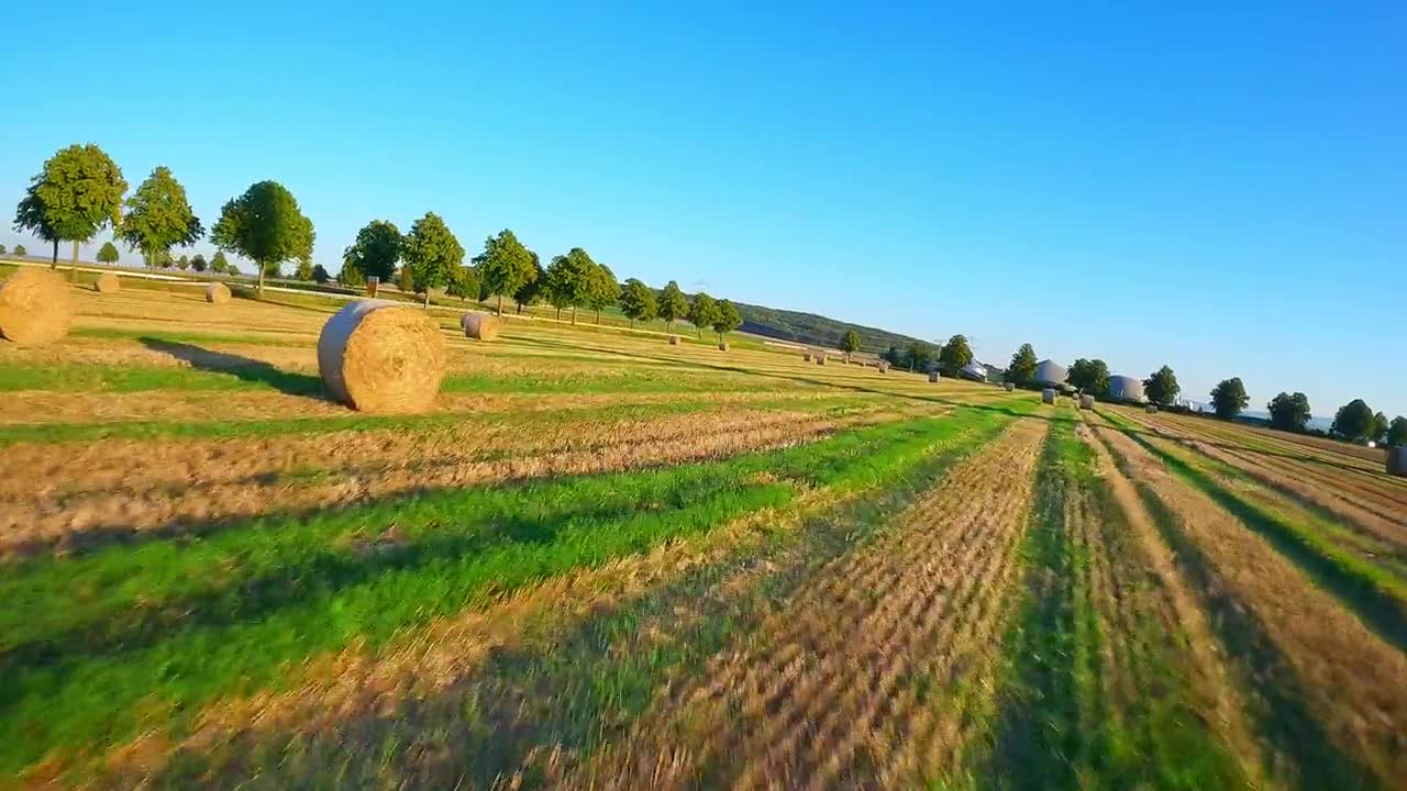 航拍FPV穿越机在德国乡村的草垛和风力涡轮机间进行电影感飞行视频素材画面1