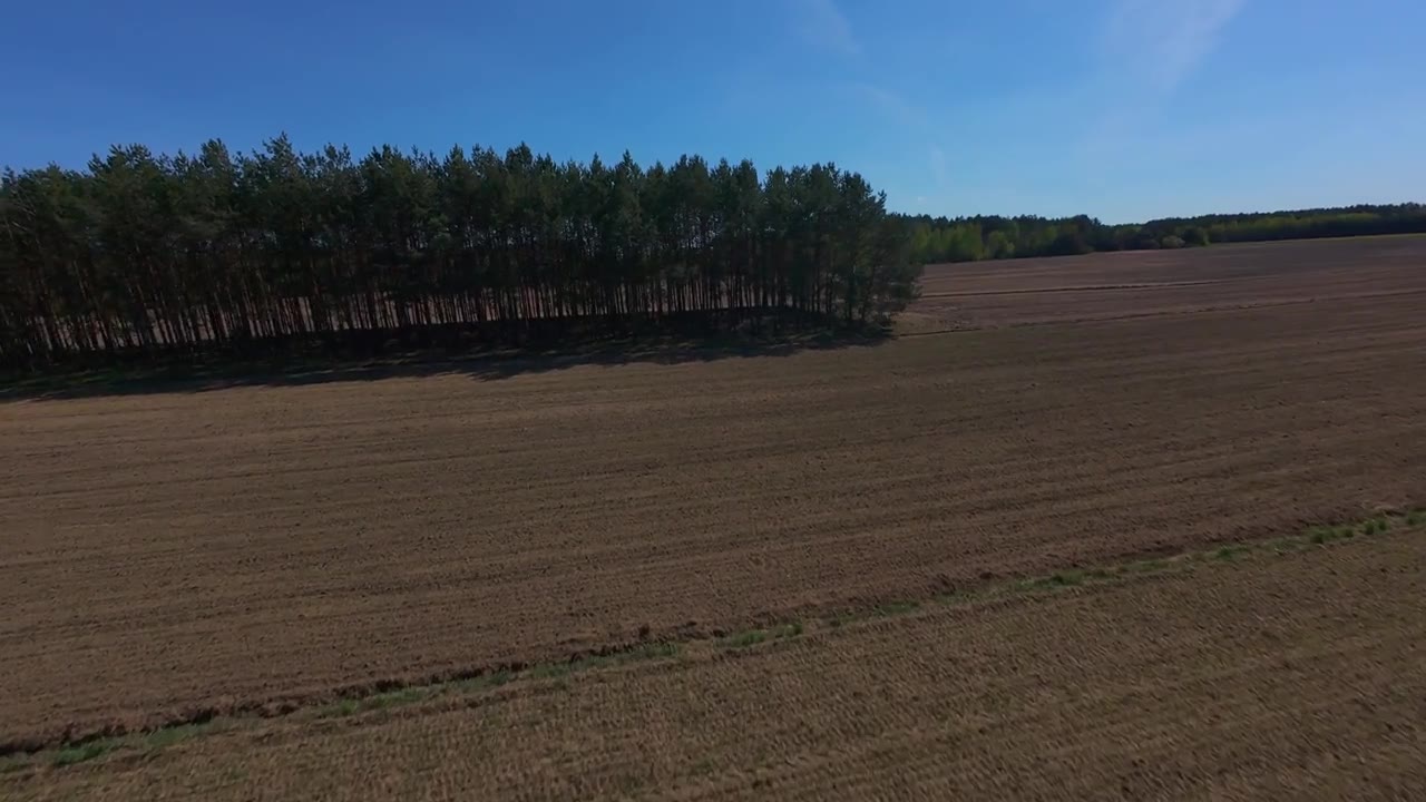 FPV穿越机飞越农田与森林边缘视频素材画面1