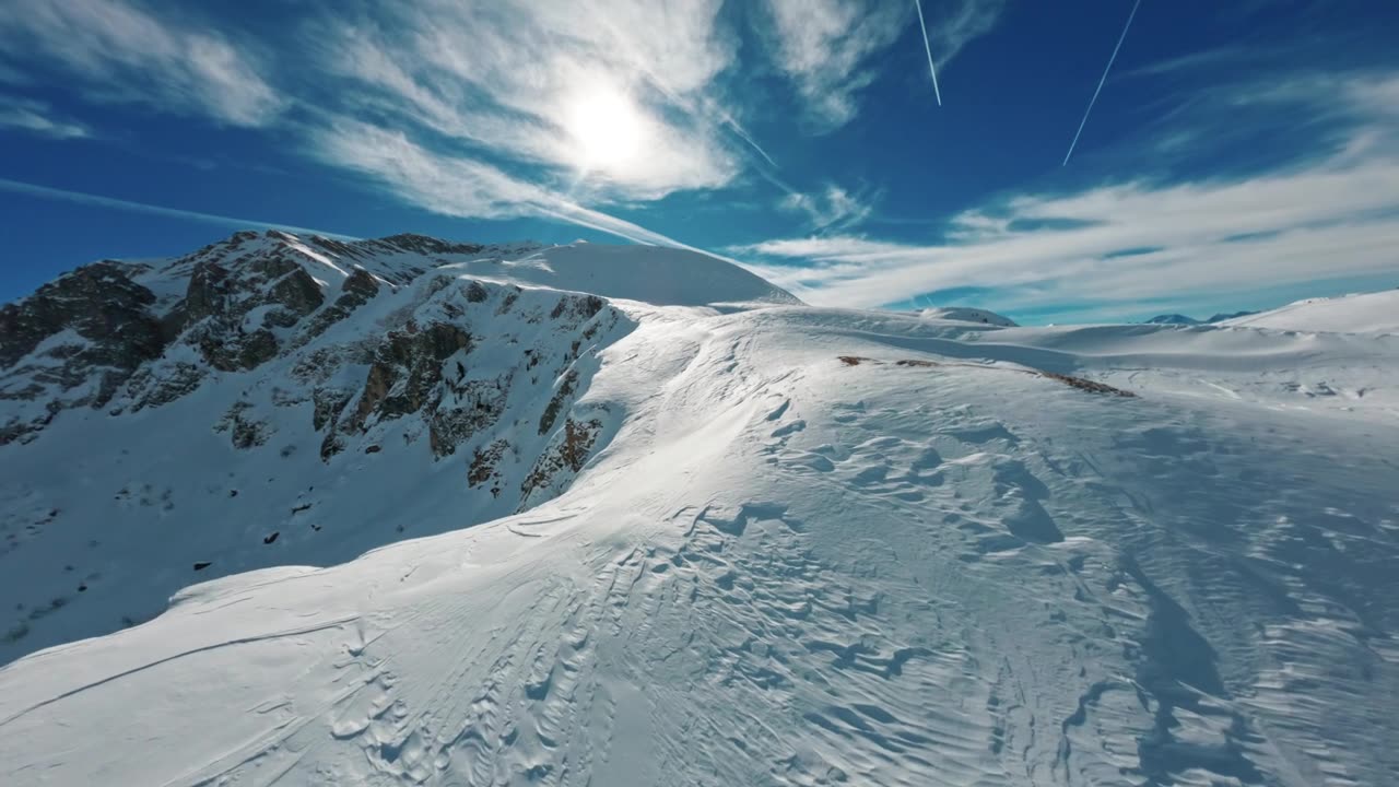 FPV穿越机在晴朗天空下掠过白雪皑皑的阿格纳尔特里山视频素材画面1
