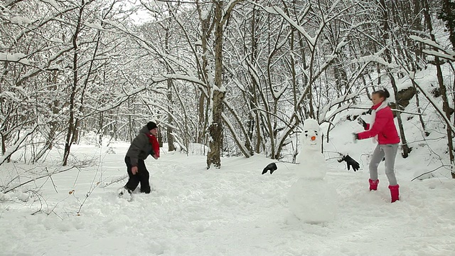 年轻夫妇在冬天的森林里扔雪球视频素材