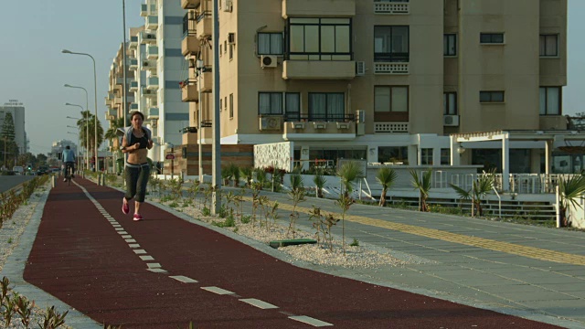 苗条的女士沿着城市道路慢跑。积极的生活方式促进健康视频素材