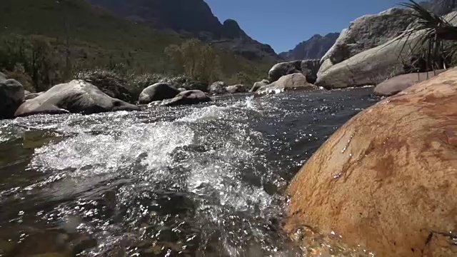 慢动作拍摄的水流过岩石的河流，从水位与山的背景视频素材