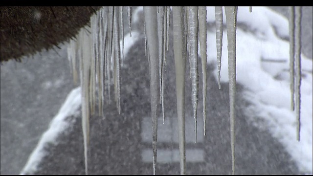 挂在屋檐上的冰柱和飘落在Gifu Gasshozukuri房屋上的大雪视频素材