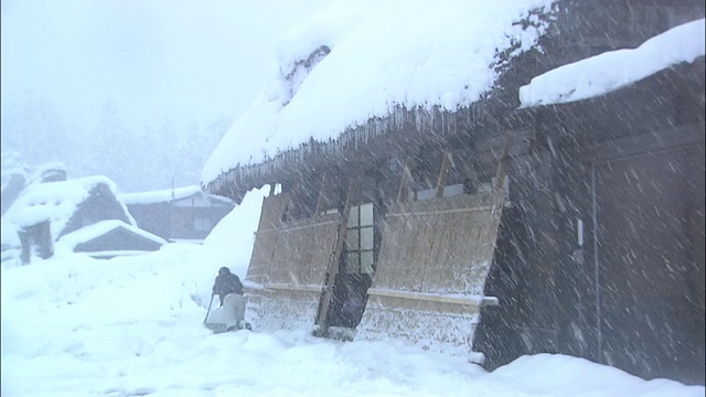 Gifu白川县，一名男子在大雪中清理Gasshozukuri房子外的积雪视频素材