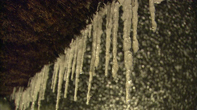 在岐阜县白川市，大雪纷飞之际，冰柱悬挂在Gasshozukuri屋的茅草屋顶上视频素材