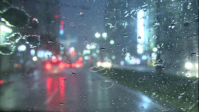 雨水落在城市街道上行驶的汽车的挡风玻璃上。视频素材