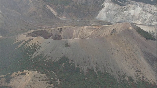 在日本的东马-小富士火山口周围，一片片的雪依附在树木繁茂的山坡上。视频素材