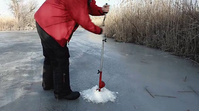 一个渔夫在冰上钻了个洞视频下载