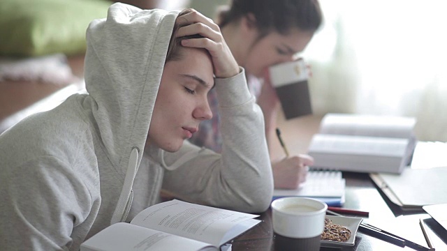 疲倦的穿着帽衫的男学生睡着了。视频素材