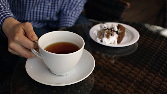 一个女人在餐厅边喝茶边吃蛋糕视频素材