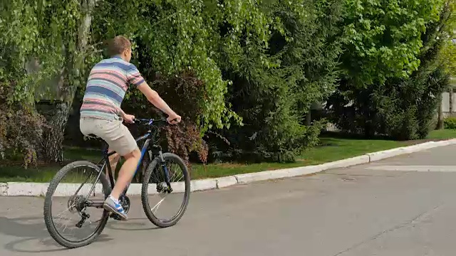 一名男子骑着自行车沿街而行。视频素材