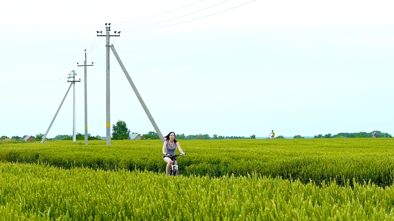 女孩骑着自行车在田野里走在路上视频素材