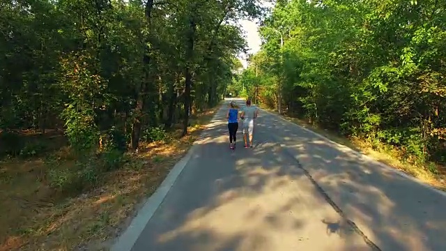 鸟瞰图的夫妇沿着森林的道路慢跑视频素材