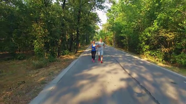 一对夫妇沿着森林中的道路慢跑视频素材