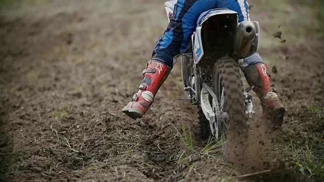 越野摩托车手开始骑他的越野MX摩托车扬起尘土后视镜，慢动作视频素材