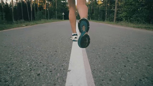 缓慢的运动。近距离观察一个面目全非的女人在一条路上跑过树林视频素材