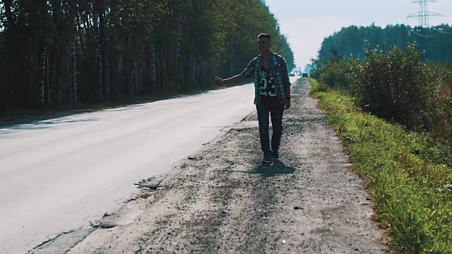 心烦意乱的男人背着背包走在路上。搭便车。拇指。旅行者视频素材画面1