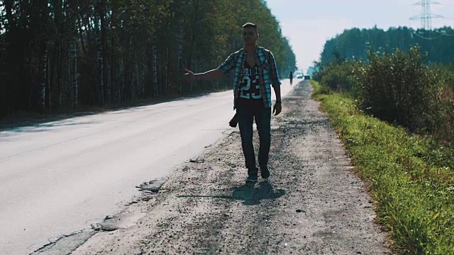 心烦意乱的男人背着背包走在路上。搭便车。拇指。旅行者视频素材画面2